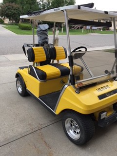 The back of a yellow golf cart with custom black and yellow seats