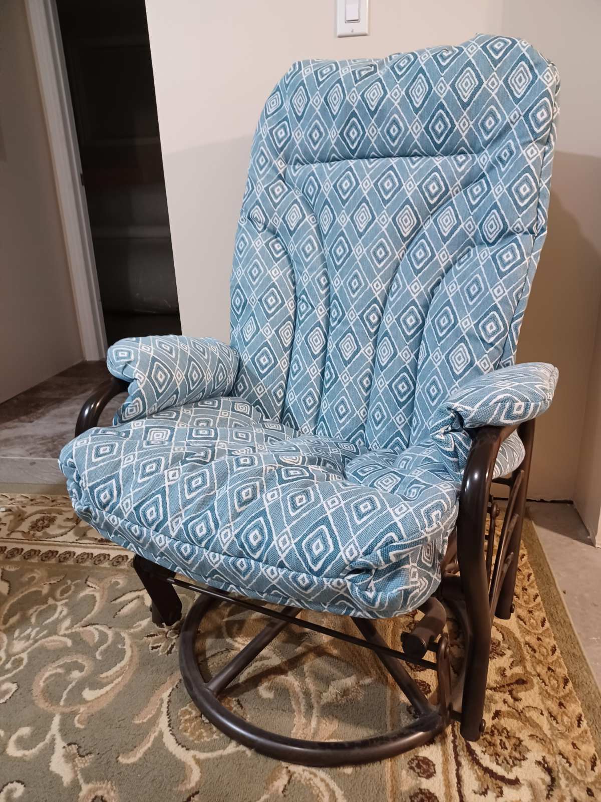 A wooden glider rocking chair with blue and white diamond-patterned upholstery